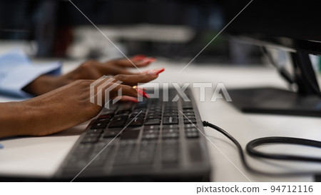 African woman is typing on the keyboard. Close-up of female hands of an office worker. African woman is typing on the keyboard. Close-up of female hands of an office worker. 94712116