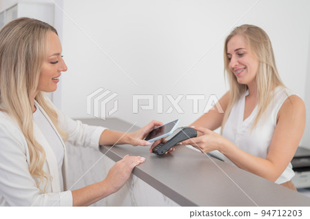 A woman pays using a non -contact payment of the NFC used by a smartphone.  94712203