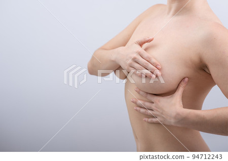 Caucasian woman self checks for breast cancer on white background. Copy space.  94712243