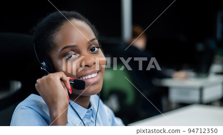 African young woman talking to a client on a headset. Female employee of the call center. 94712350