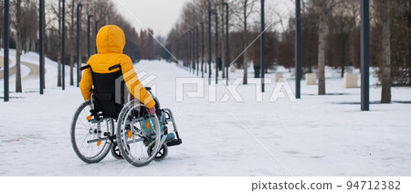Woman in wheelchair relaxing in winter park.  94712382