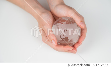 Crystal globe in female hands on a white background. Crystal globe in female hands on a white background. 94712383