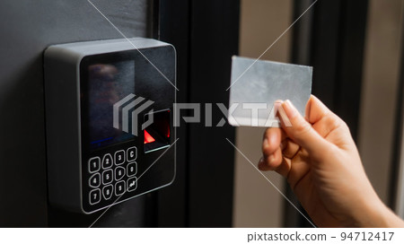 A woman opens the door with a plastic card. Modern keyless entry lock. A woman opens the door with a plastic card. Modern keyless entry lock. 94712417