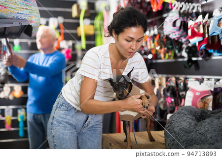 Woman dressing her dog in pet shop 94713893