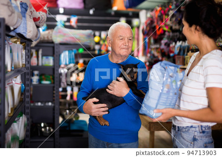 Senior man choosing dog food in pet shop Senior man choosing dog food in pet shop 94713903