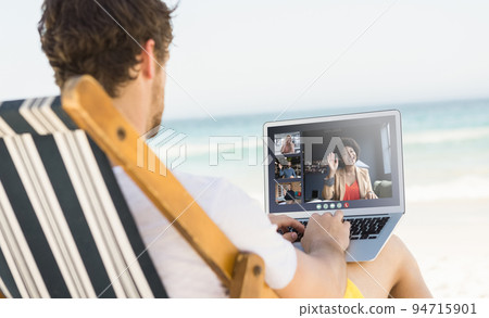 Caucasian man relaxing on beach having video call using laptop 94715901