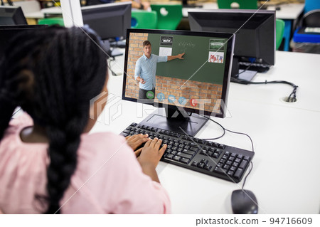 Mixed race schoolgirl using computer on video call with male teacher Mixed race schoolgirl using computer on video call with male teacher 94716609