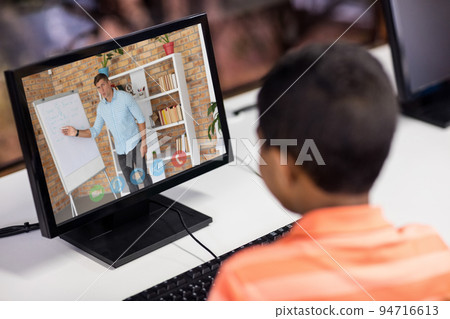 Mixed race schoolboy using computer on video call with male teacher Mixed race schoolboy using computer on video call with male teacher 94716613