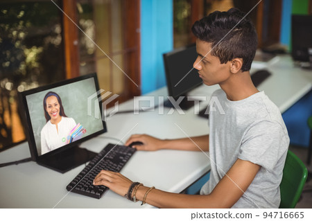 Mixed race schoolboy using computer on video call with female teacher Mixed race schoolboy using computer on video call with female teacher 94716665