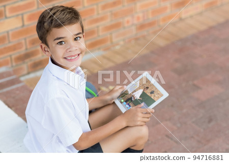 Portrait of smiling caucasian schoolboy using digital tablet on video call with male teacher 94716881