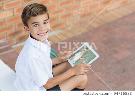 Portrait of smiling caucasian schoolboy using digital tablet on video call with female teacher Portrait of smiling caucasian schoolboy using digital tablet on video call with female teacher 94716888