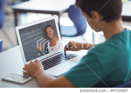 Caucasian schoolboy using laptop on video call with female teacher 94716907