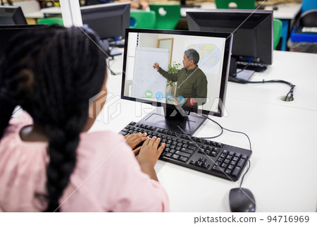 Female student having a video call with male teacher on computer at school Female student having a video call with male teacher on computer at school 94716969