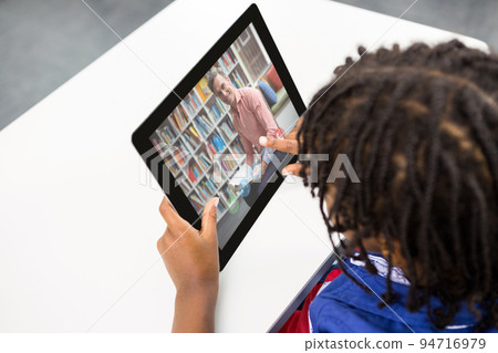 Mixed race schoolboy using digital tablet on video call with male teacher Mixed race schoolboy using digital tablet on video call with male teacher 94716979