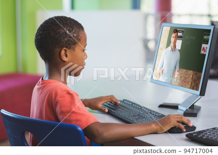 Male african american student having a video call with male teacher on computer at school 94717004