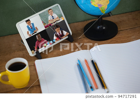 School children learning on tablet screen on desk during video call 94717291