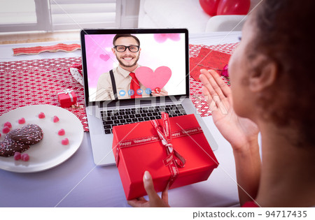 Diverse couple making valentines date video call the woman blowing kiss to man on laptop screen Diverse couple making valentines date video call the woman blowing kiss to man on laptop screen 94717435