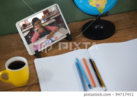 Caucasian schoolgirl learning on tablet screen on desk during video call 94717451