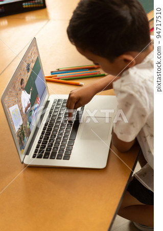 Mixed race schoolboy using laptop on video call with male teacher Mixed race schoolboy using laptop on video call with male teacher 94717510