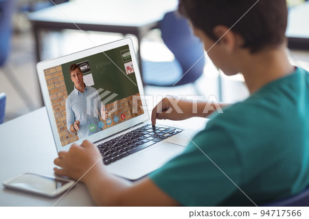 Caucasian schoolboy using laptop on video call with male teacher 94717566