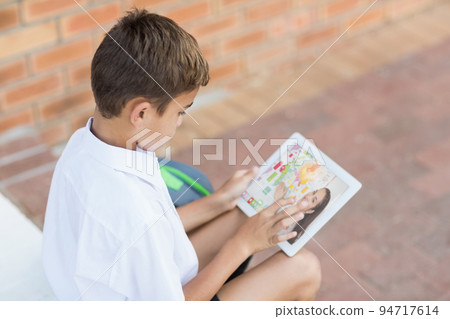 Male caucasian student having a video call with female teacher on digital tablet at school 94717614