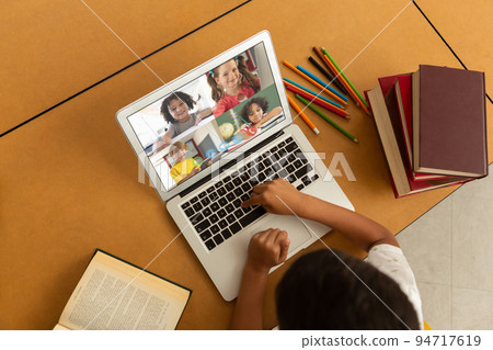 Mixed race schoolboy using laptop on video call with his school friends Mixed race schoolboy using laptop on video call with his school friends 94717619