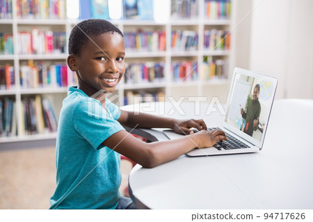 Portrait of male african american student having a video call with male teacher on laptop at library Portrait of male african american student having a video call with male teacher on laptop at library 94717626