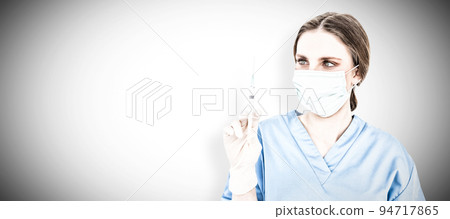 Pretty brunette female doctor holding a syringe and looking at it. Testing for Coronavirus pandemic 94717865