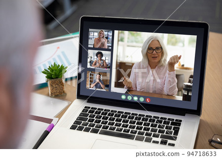 Diverse business people displayed on laptop screen during office video call Diverse business people displayed on laptop screen during office video call 94718633