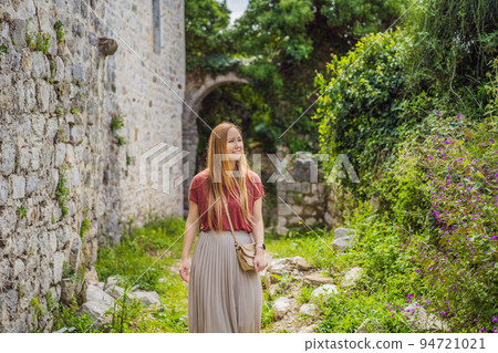 Woman tourist walks through the old town of Bar in Montenegro. Happy tourist walks in the mountains. Suburbs of the city of Bar, Montenegro, Balkans. Beautiful nature and landscape 94721021