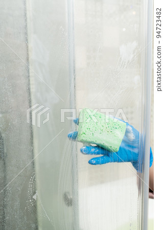A woman cleans a shower cabin from limestone 94723482