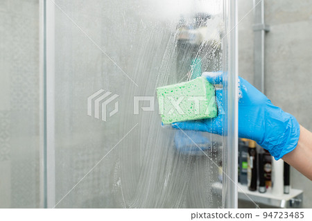 A woman cleans a shower cabin from limestone 94723485