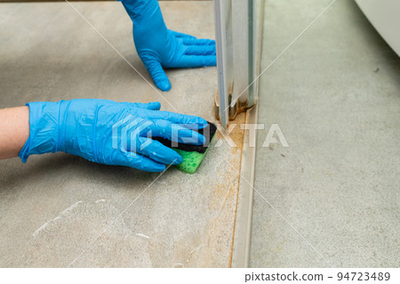 A woman cleans a shower cabin from limestone A woman cleans a shower cabin from limestone 94723489
