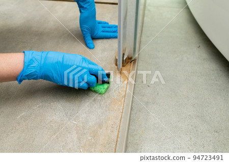 A woman cleans a shower cabin from limestone 94723491