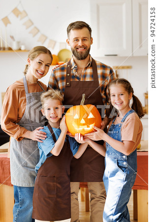 Happy family mother, father and kids smiling at camera make jack-o-lantern from pumpkin, getting ready for halloween 94724158