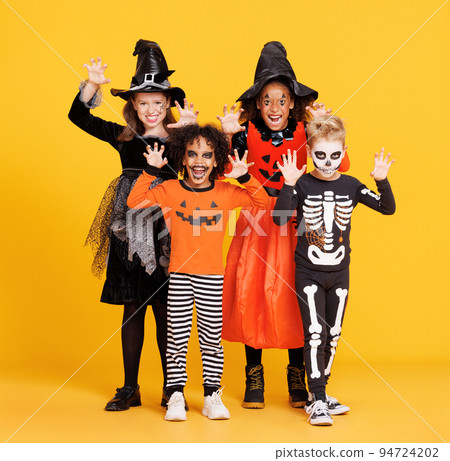 Happy Halloween. Kids in carnival costumes and makeup make a terrible gesture on bright colored yellow background 94724202