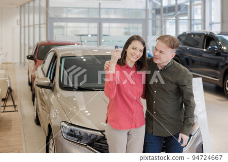 man and a woman couple in a car dealership buy or trade in. car rental or repair service. happy and successful  94724667