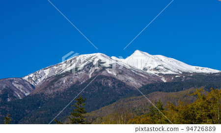 Norikura-dake covered with snow and autumn leaves 94726889
