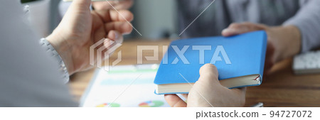 Businesspeople exchange notebooks in office, men give to each other books 94727072