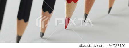 Tips of group of pencils put on paper in strict order, red among black pens 94727101