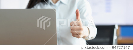 Office clerk showing thumbs up gesture working on laptop Office clerk showing thumbs up gesture working on laptop 94727147