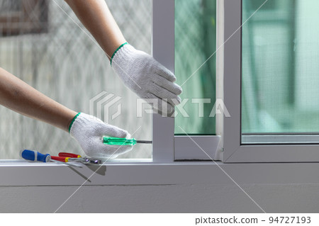 Construction worker repairing the sliding window. 94727193