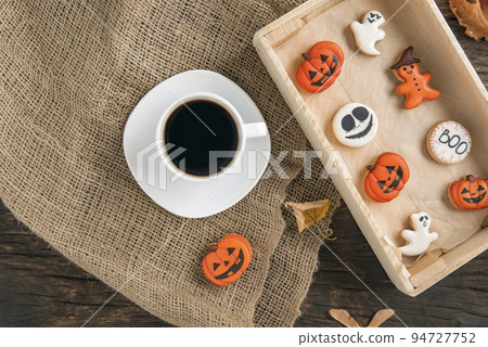 Halloween gingerbread on brown wooden table and Cup of coffee. Cookie pumpkin and ghost. Top view 94727752