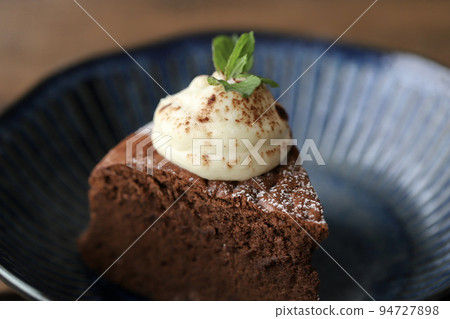 Cut chocolate cake decorated with fresh cream and mint 94727898