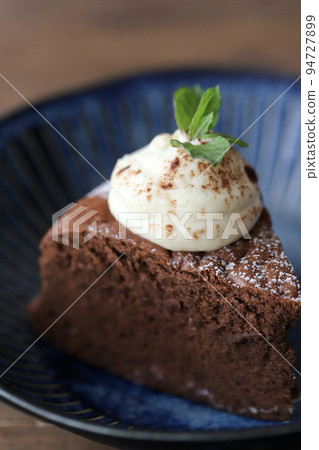 Cut chocolate cake decorated with fresh cream and mint Cut chocolate cake decorated with fresh cream and mint 94727899