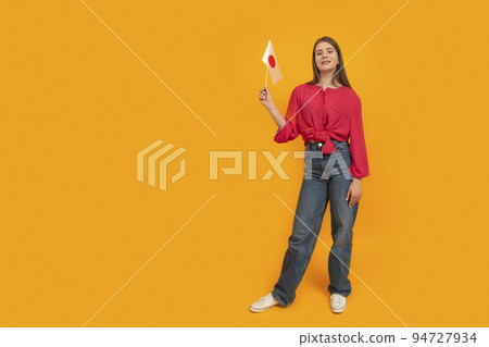 Full-length portrait of teenage girl with the flag of Japan on orange background. Learn Japanese. Study and travel to Japan. Space for text 94727934