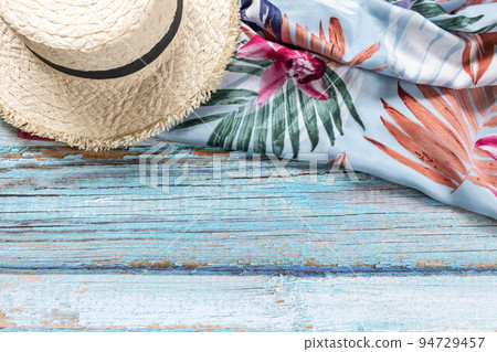 A straw hat and a blue scarf on the light blue wooden background. Beach and Summer concept. 94729457
