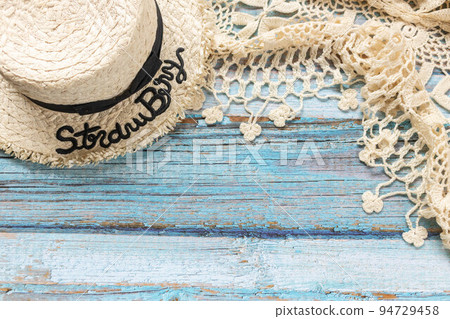 A straw hat and a white knitting scarf on the light blue wooden background. Beach and Summer concept. A straw hat and a white knitting scarf on the light blue wooden background. Beach and Summer concept. 94729458