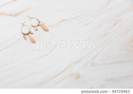 A pair of earrings on a marble background with copy space. 94729463