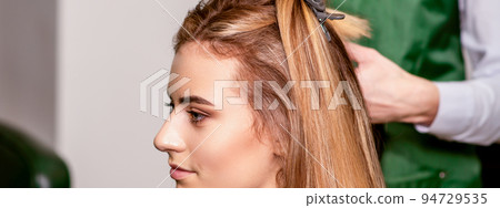 Professional hair care. Beautiful young caucasian blonde woman with long hair receiving hairstyling in a beauty salon Professional hair care. Beautiful young caucasian blonde woman with long hair receiving hairstyling in a beauty salon 94729535